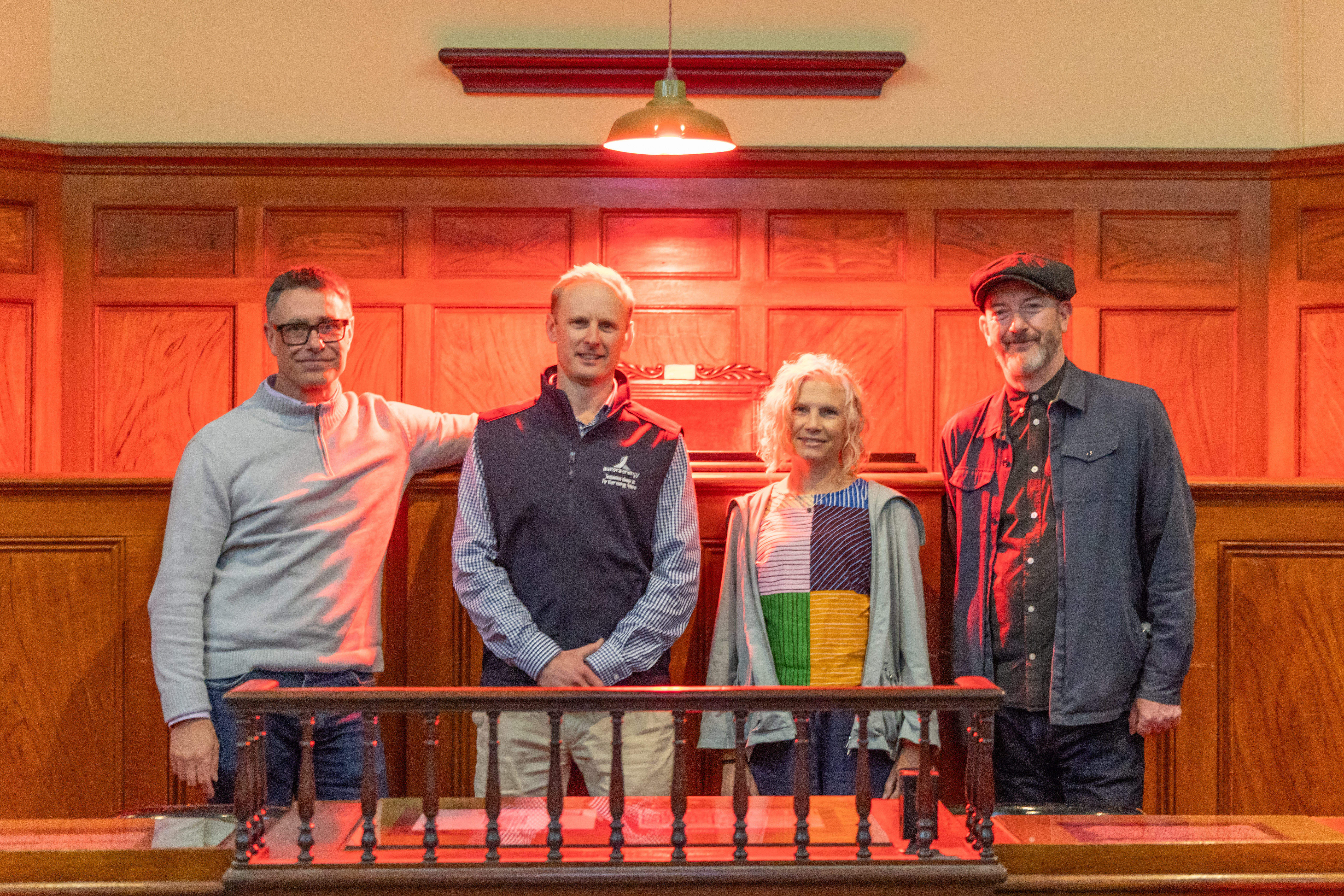 image of four people at the Paint the Town Red press release, with red lighting