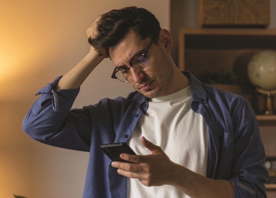 Man looking at his phone with a puzzled expression