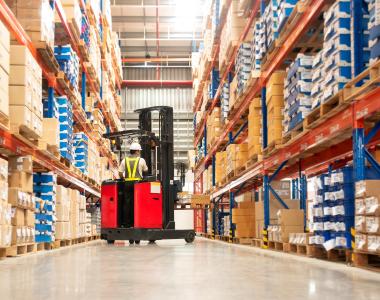 Forklift in warehouse with shelves either side full of boxes